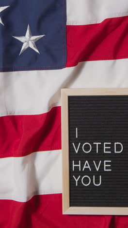 Vertical-Video-Of-Sign-Reading-I-Voted-Have-You-Lying-On-US-Stars-And-Stripes-Flag-For-American-Election-2024-1